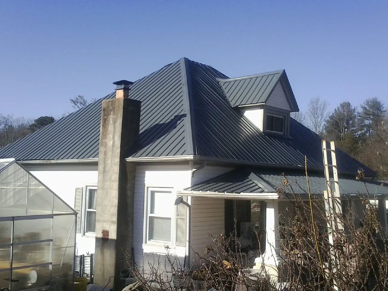 Dark blue standing seam metal roof on a white farmhouse with dormer — Slate & Tile Roof Repair by Roofing Brothers in Panama