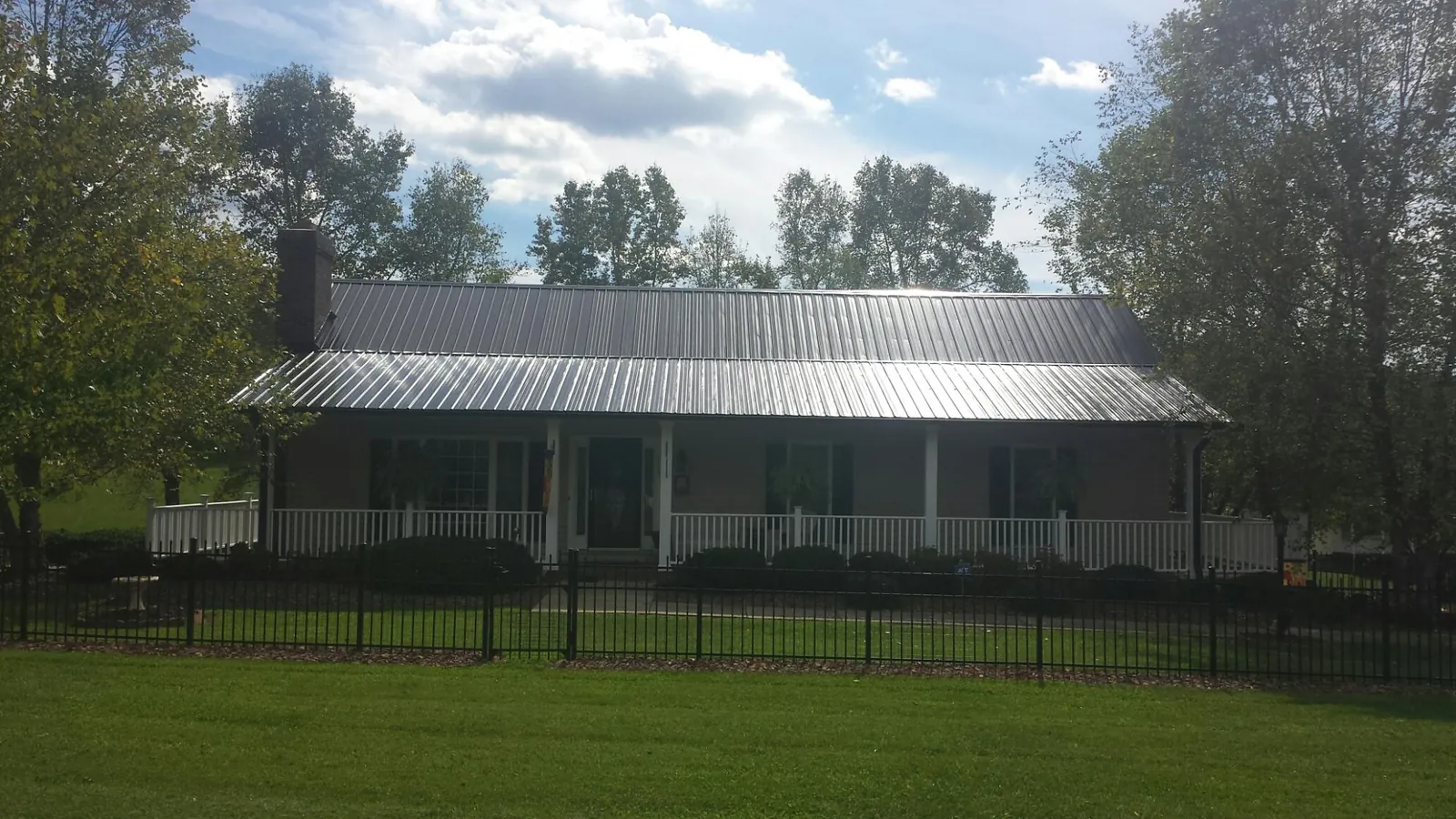 Gray metal roof on a brick ranch with a full width front porch — Gutter Guard Installation work by our crew in Panama