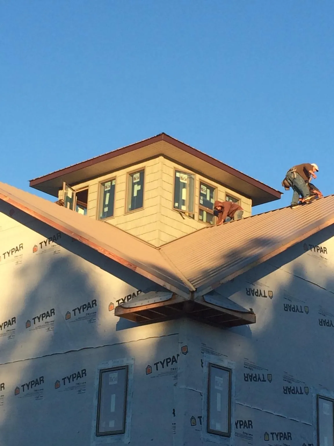 Roofers working around a rooftop cupola on a new metal roof at sunset — Roof Waterproofing in Panama by Roofing Brothers